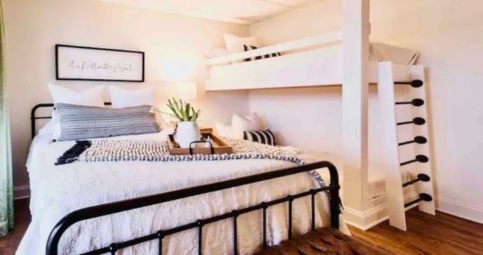 A queen size bed next to a set of built-in bunk beds